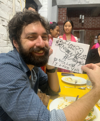 Volontario di Skillando in Bangladesh che sorride mentre osserva un disegno realizzato dai bambini locali.