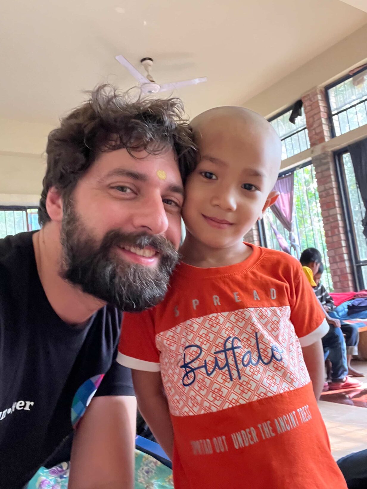 Ritratto di un volontario di Skillando con un bambino.