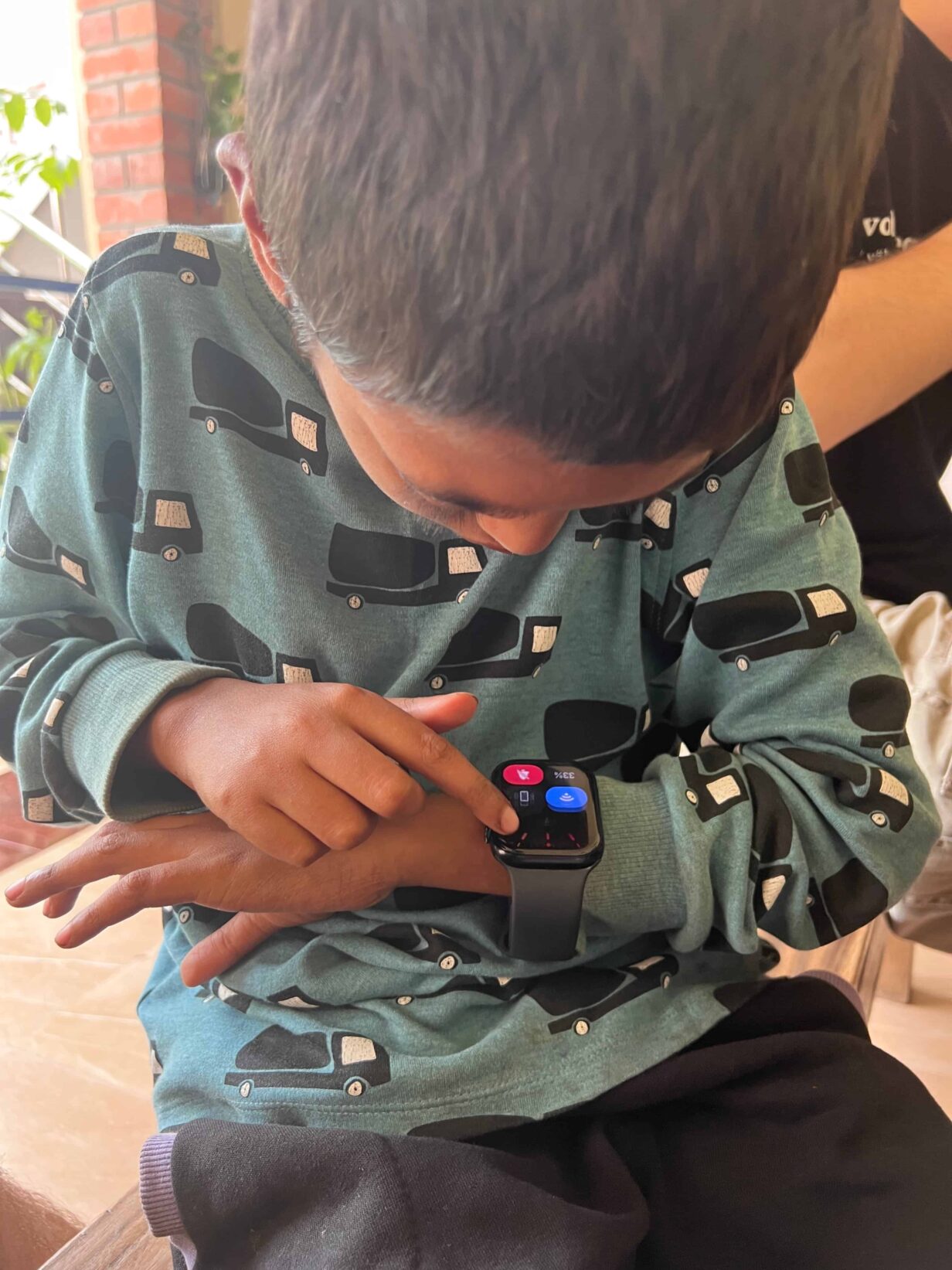 "Un bambino del Bangladesh concentrato mentre esplora e cerca di capire come funziona uno smartwatch.