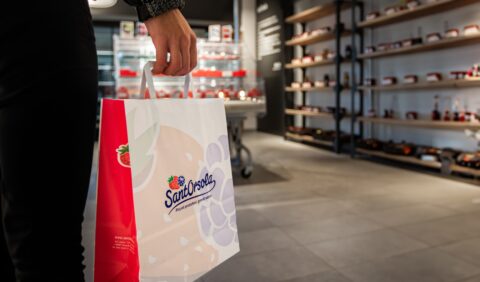 Un sacchetto di carta con il logo Sant'Orsola, tenuto in mano all'interno di un negozio.